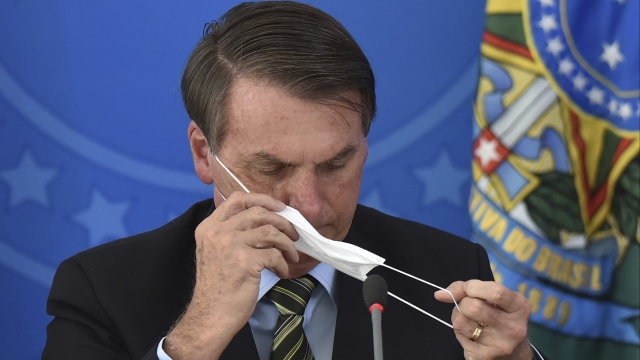 Brazil's President Jair Bolsonaro puts on a mask during a coronavirus press conference on March 18.