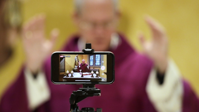 A cell phone is used to live stream mass by Archbishop Paul D. Etienne at St. James Cathedral