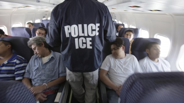 A 2010 file image of an ICE agent walking by detainees during a deportation flight