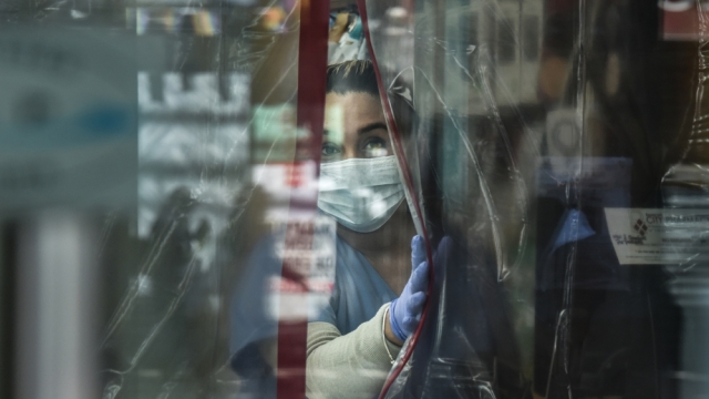 A photograph taken by Stephanie Keith depicts a pharmacist wearing personal protective equipment in Queens, New York.