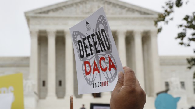 A protester with a poster that says 'Defend DACA' in front of the Supreme Court.