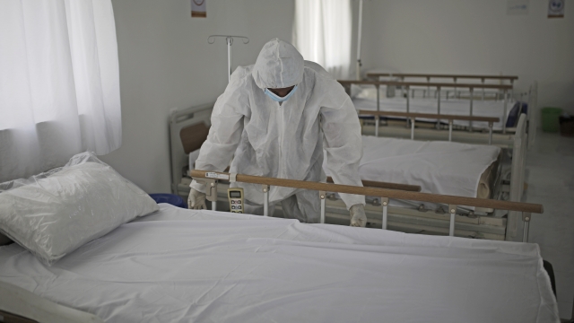 A medical staff member adjusts the sheets on a bed at a hospital in Yemen