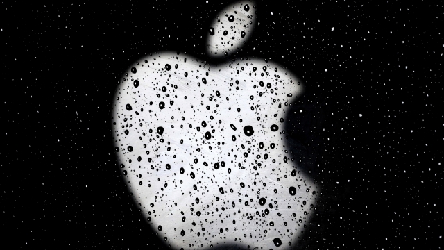 Apple logo seen through glass pane with water droplets on it