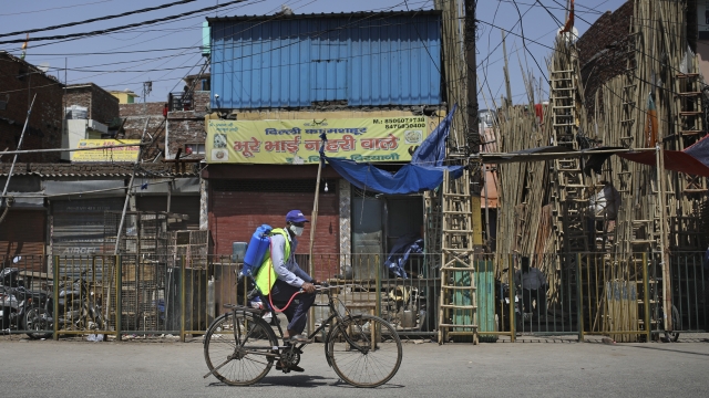 A civic worker in India pedals past an area which was sealed following suspected cases of COVID-19