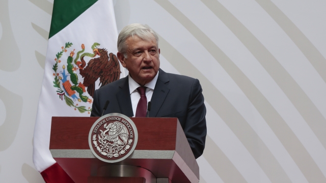 Mexico President Andres Manuel Lopez Obrador standing at a podium with the Mexican flag behind him