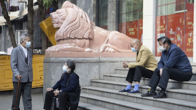 Wuhan residents sit on steps outside a bank.