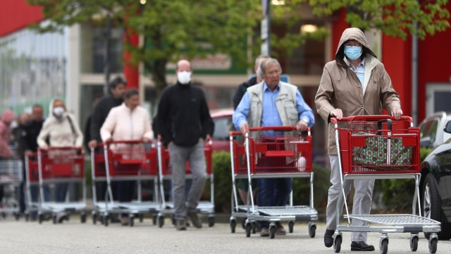 People wearing protective masks queue up to go in a garden store in Munich, Germany