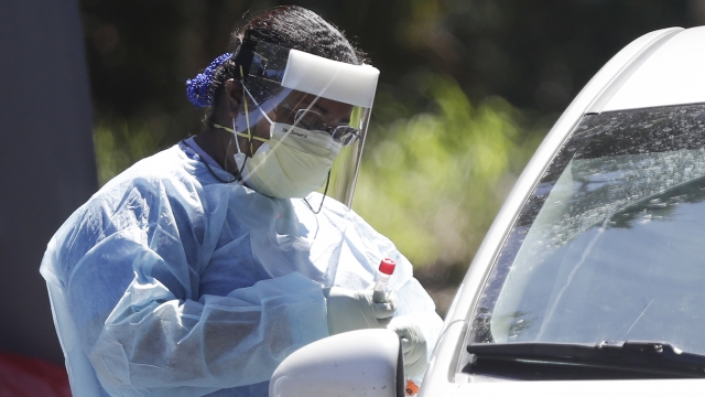 A health worker conducts COVID-19 tests at a drive through coronavirus testing site in Florida