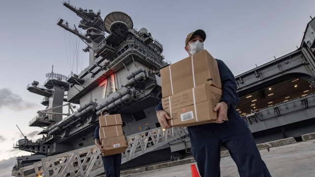 USS Theodore Roosevelt crew moves boxed meals for sailors who can stay on ship after testing negative for virus.