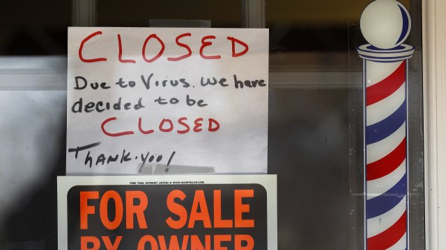 "For Sale By Owner" and "Closed Due to Virus" signs are displayed in the window of a store.