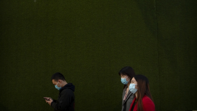 People wear face masks while walking in Beijing