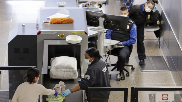 TSA agents wear masks as they screen passengers at Seattle-Tacoma International Airport Wednesday, April 15, 2020