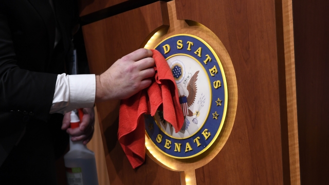 Man wiping down the U.S. Senate logo on a podium before a press conference