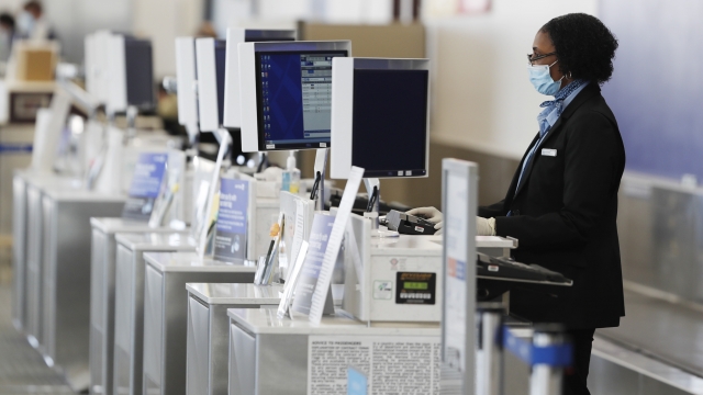 A ticketing agent wears a face mask while waiting for passengers at the United Airlines counter at Colorado Springs Airport