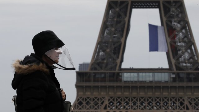 A man wears a mask near the Eiffel Tower