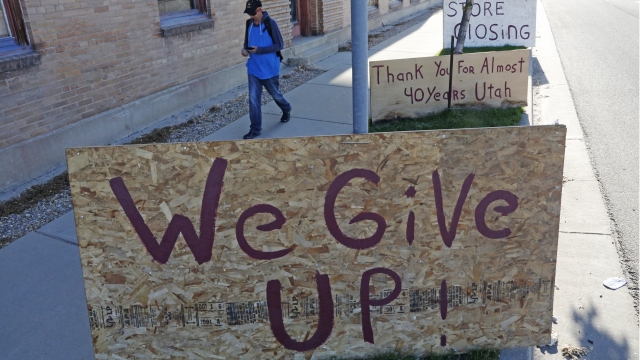 A man walks past a "we give up" sign outside Euro Treasures Antiques Friday, May 8, 2020, in Salt Lake City