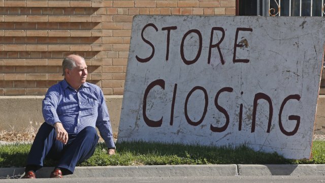 A business owner poses next to a closing sign