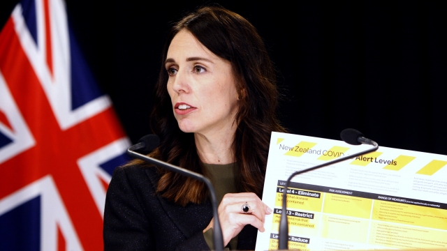 New Zealand Prime Minister Jacinda Ardern holds up a card showing an alert system for COVID-19