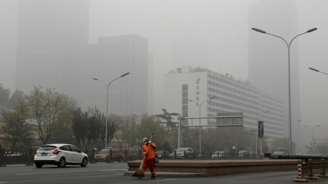 A man wearing a mask sweeps a street in Beijing
