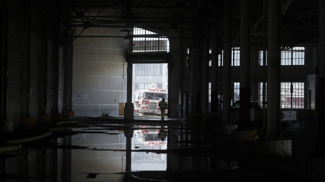 A fire official is shown reflected in a puddle in a warehouse after a fire broke out before dawn at Fisherman's Wharf.