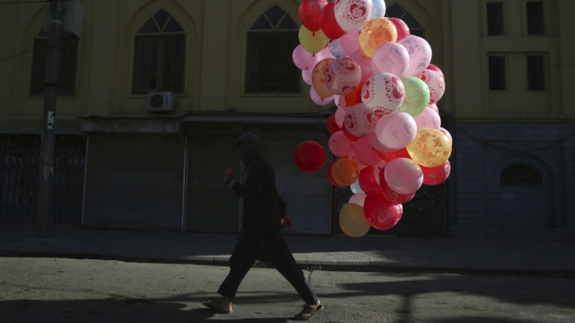A man walks with colored balloons for sale during the first day of Eid al-Fitr