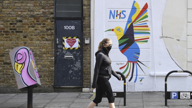 A person walks past a mural painted on the side of a pharmacy in Stoke Newington area of London