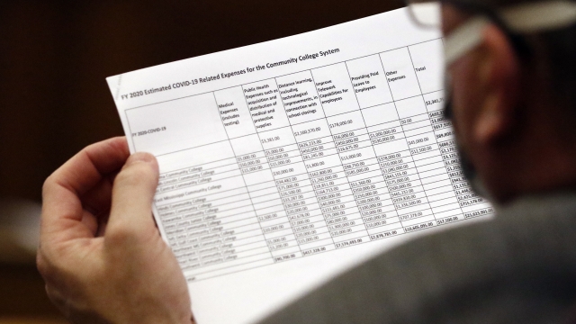 A state senator reviews a document that lists the estimated expenses to the state's community colleges.