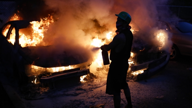 Protesters attempt to extinguish car fires on East Lake Street, Friday, May 29, 2020, in St. Paul, Minnesota