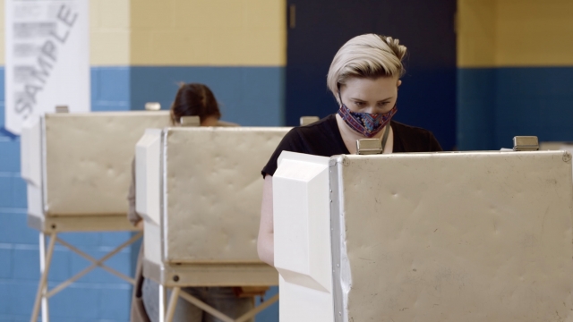 Voters cast ballots while wearing masks.