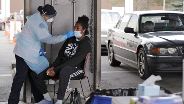 Nyasha Sarju sits as a Seattle Fire Department paramedic prepares takes a nasal swab sample to test for coronavirus at a test