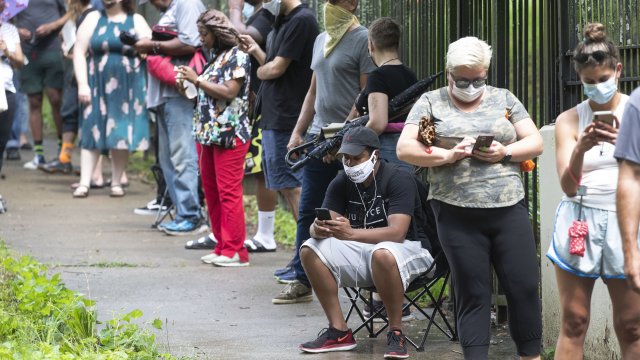 A man checks his phone as he waits in line to vote.