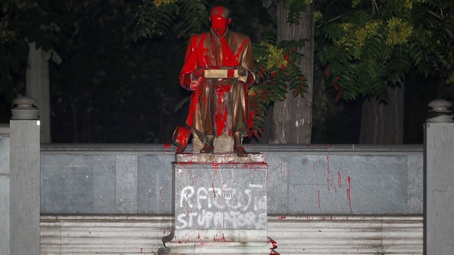 Red paint and words in Italian reading "racist," above, and "rapist" are seen on a statue of a late Italian journalist