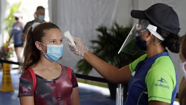 A guest has her temperature checked before entering SeaWorld as it reopens with new safety measures in place.