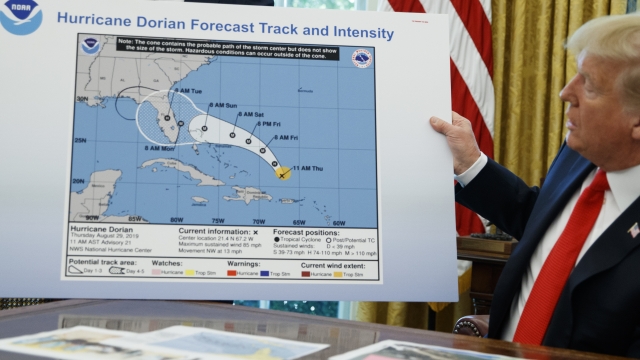 President Donald Trump holds a chart as he talks with reporters after receiving a briefing on Hurricane Dorian.