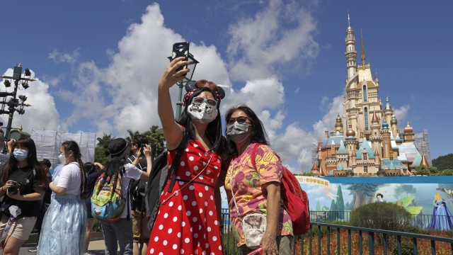 Visitors wearing face masks to prevent the spread of the new coronavirus, take a selfie at the Hong Kong Disneyland