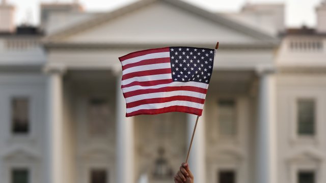 A person waves an American flag in front of the White House