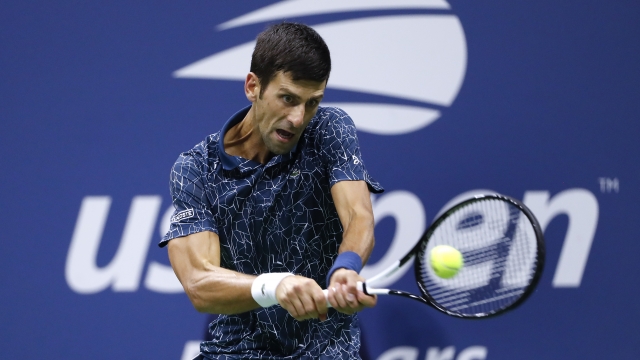 Tennis player Novak Djokovic returns a shot.