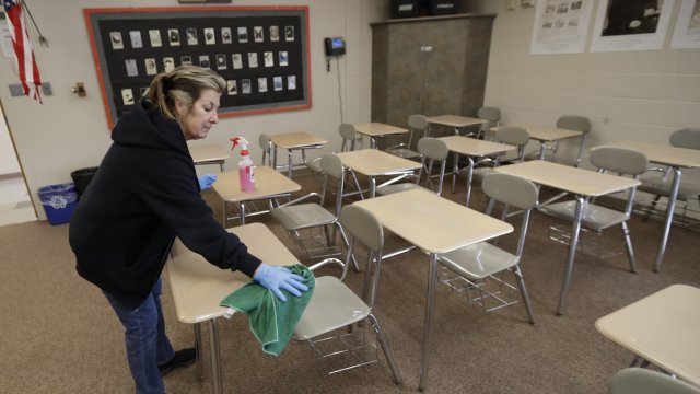 Custodian cleans classroom desks