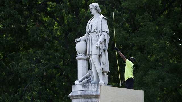 A city worker measures the statue of Christopher Columbus at Marconi Plaza