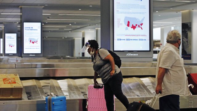 A woman wearing a mask grabs her bag in New York's Laguardia Airport