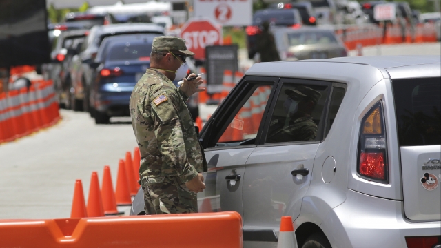 A member of the Florida National Guard talks to a driver as he monitors vehicles entering a testing site for COVID-19.