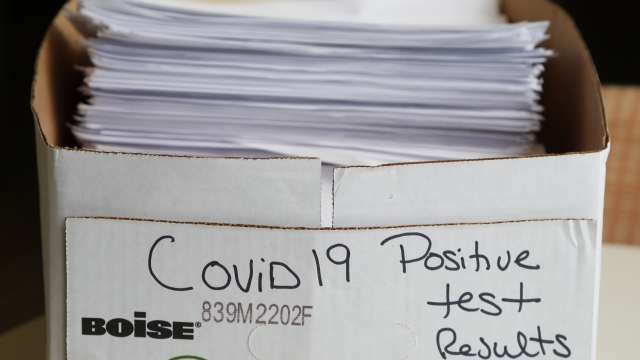 A stack of paperwork detailing positive COVID-19 test results sits in a box.