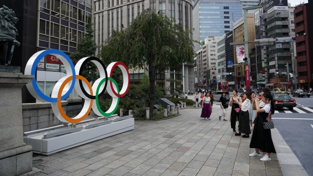People take pictures of the Olympic rings in Tokyo