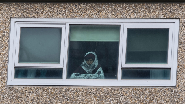 Woman looks through housing complex window
