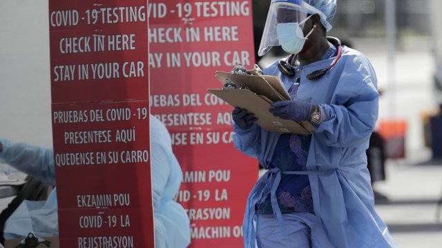 A healthcare worker carries clipboards at a Florida testing site.