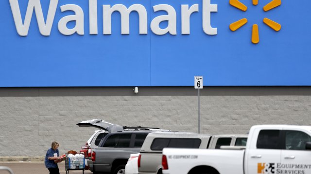 A woman pulls groceries from a cart to her vehicle outside of a Walmart store in Pearl, Miss. on March 31, 2020.