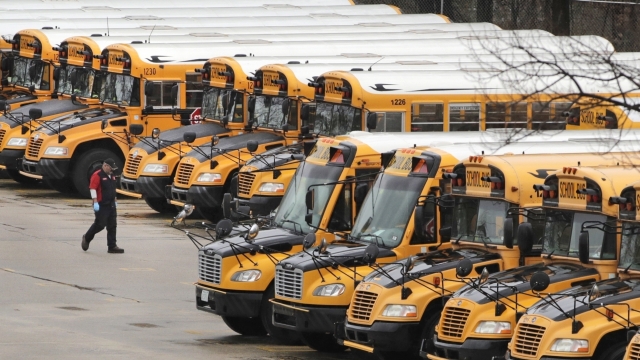 A worker passes public school buses parked at a depot in Manchester, N.H.