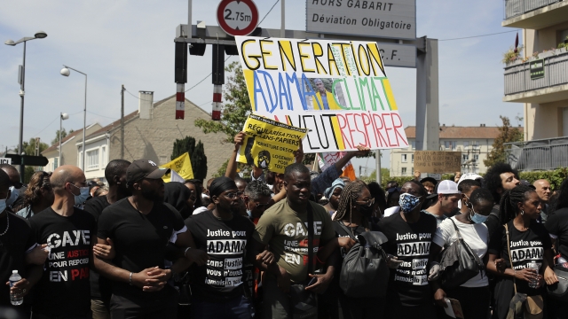 Demonstrators holding a placard reading "Generation Adama-Climate, we want to breathe" take part of a march