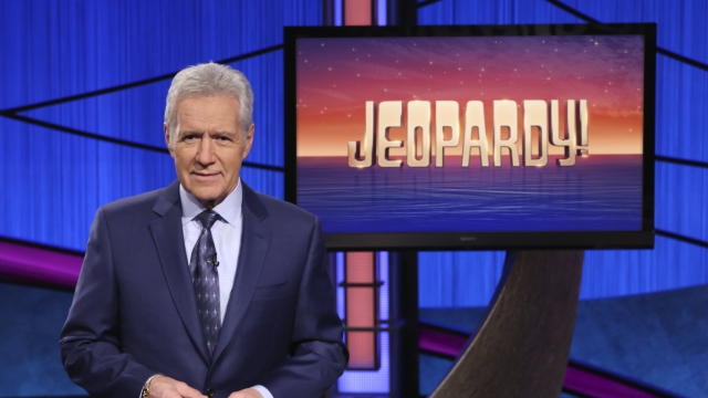 Alex Trebek in front of "Jeopardy!" logo