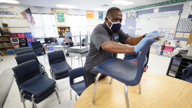 Des Moines Public Schools custodian Tracy Harris cleans chairs in a classroom at Brubaker Elementary School